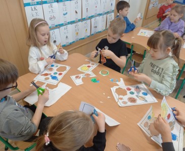 Na zdjęciu dzieci wykonują pracę plastyczną ,,Wirujące planety'.  - powiększ