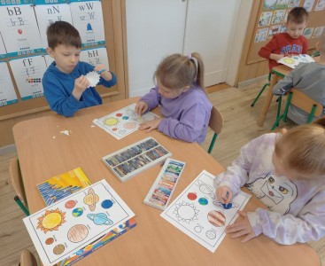 Na zdjęciu dzieci wykonują pracę plastyczną ,,Wirujące planety'.  - powiększ