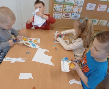 Na zdjęciu dzieci wykonują pracę plastyczną ,,Wirujące planety'.  - powiększ