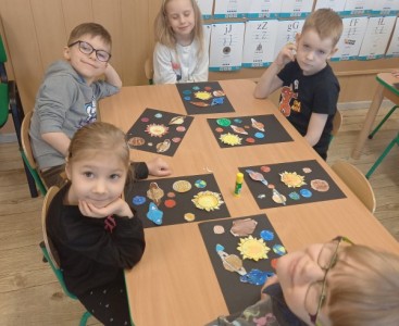 Na zdjęciu dzieci wykonują pracę plastyczną ,,Wirujące planety'.  - powiększ