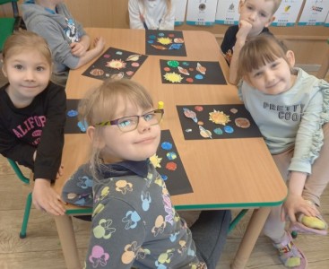 Na zdjęciu dzieci wykonują pracę plastyczną ,,Wirujące planety'.  - powiększ