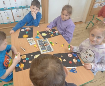 Na zdjęciu dzieci wykonują pracę plastyczną ,,Wirujące planety'.  - powiększ