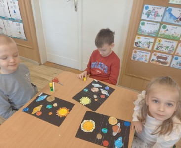 Na zdjęciu dzieci wykonują pracę plastyczną ,,Wirujące planety'.  - powiększ